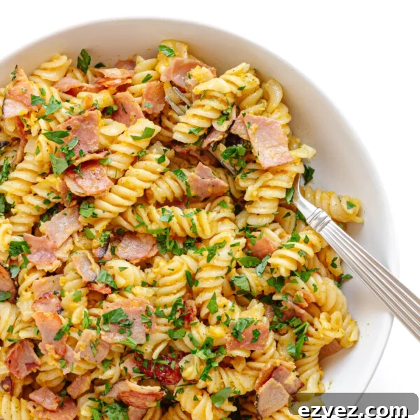 Creamy Burrata Pasta with Cherry Tomato Garlic Butter Sauce 15 Closeup of a bowl of Schinkennudeln (German Ham and Egg Pasta) with a fork scooping out a bite.