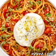 Serving bowl of pasta with cherry tomato sauce and burrata.