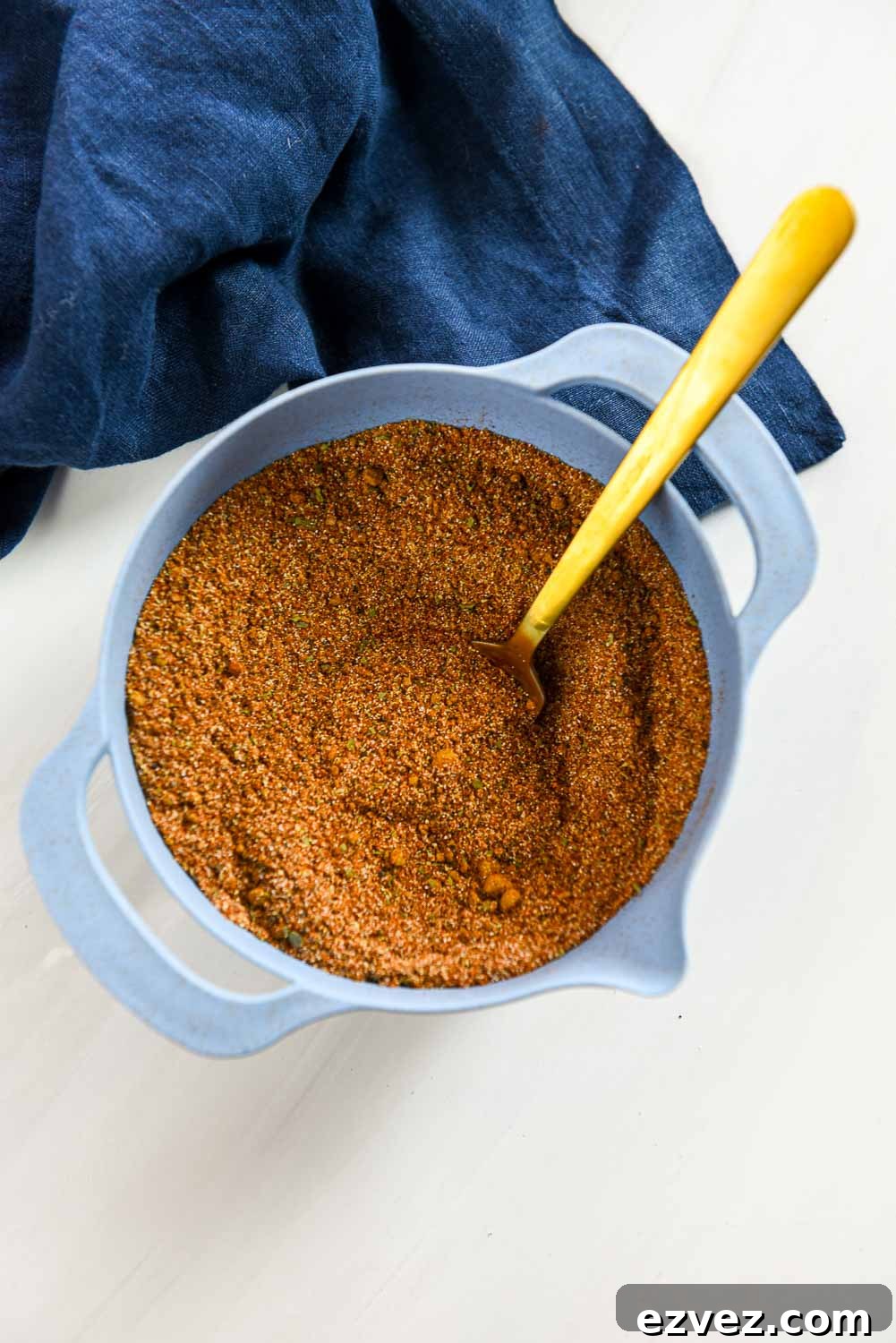 blue mixing bowl with fajita seasoning mixed with gold fork