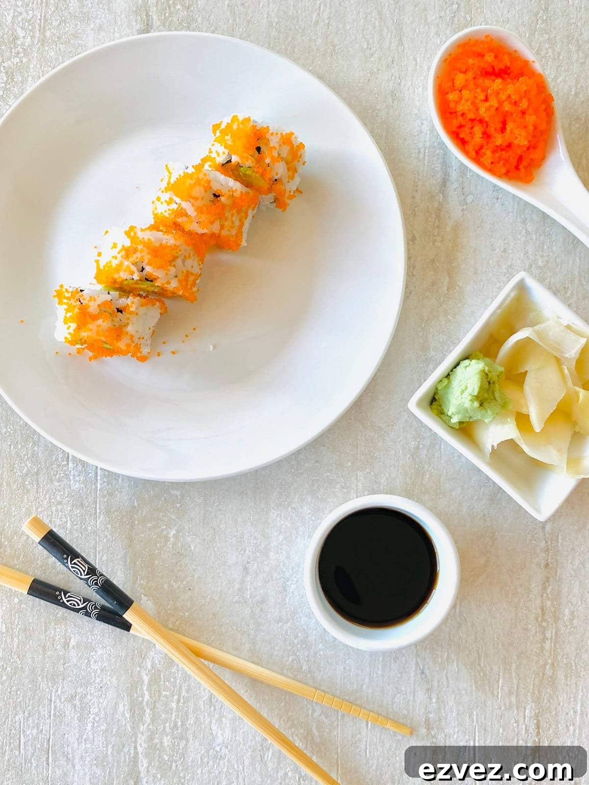 Tobiko Explained: What Tobiko Sushi Is and How It's Used 2 tobiko in a spoon next to and tobiko sushi roll