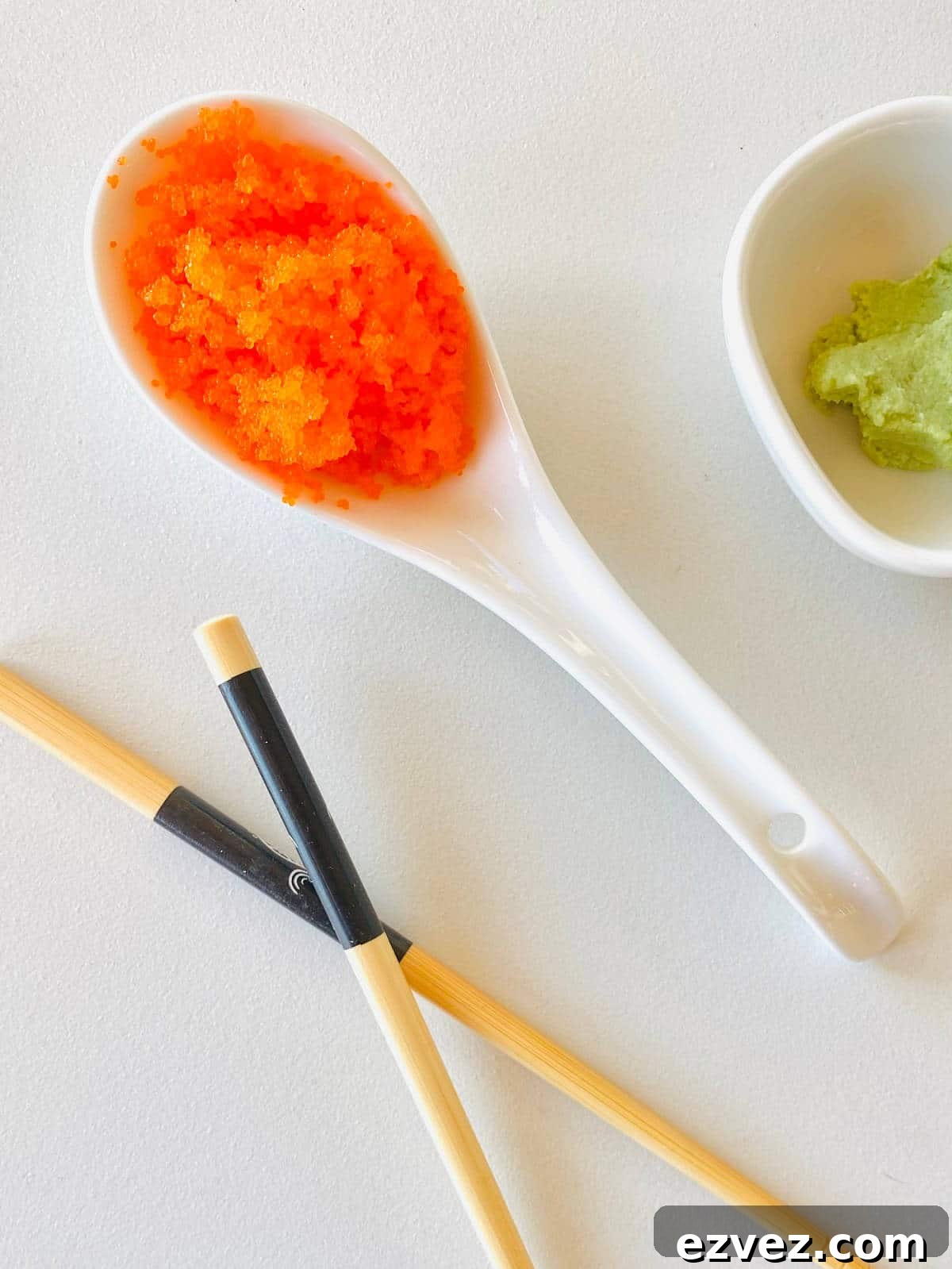 Tobiko Explained: What Tobiko Sushi Is and How It's Used 6 tobiko fish eggs in a spoon next to chopsticks and wasabi