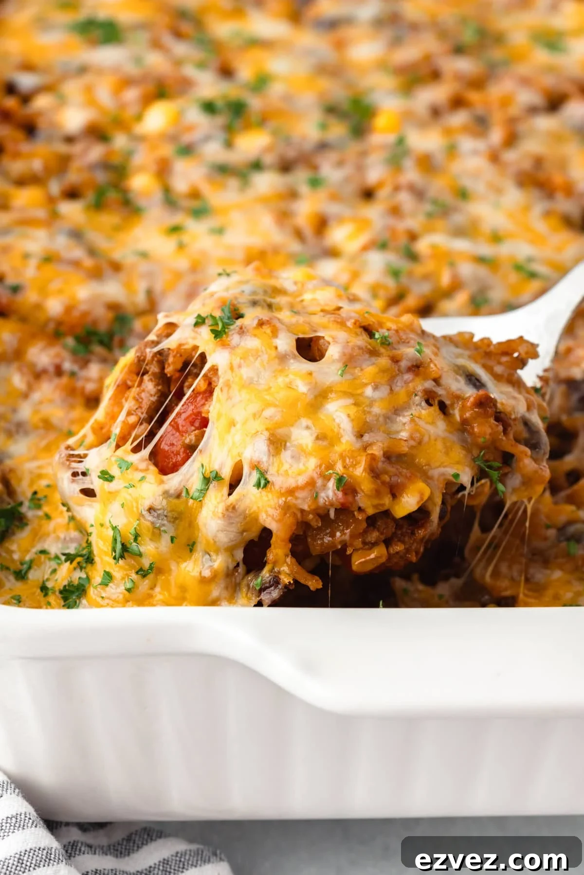 A close-up of a taco rice casserole being served from a white baking dish.