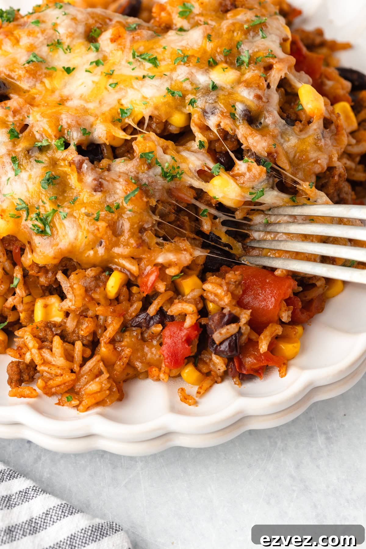A close-up of a taco rice casserole with ground beef, black beans, corn, tomatoes, and cheese.