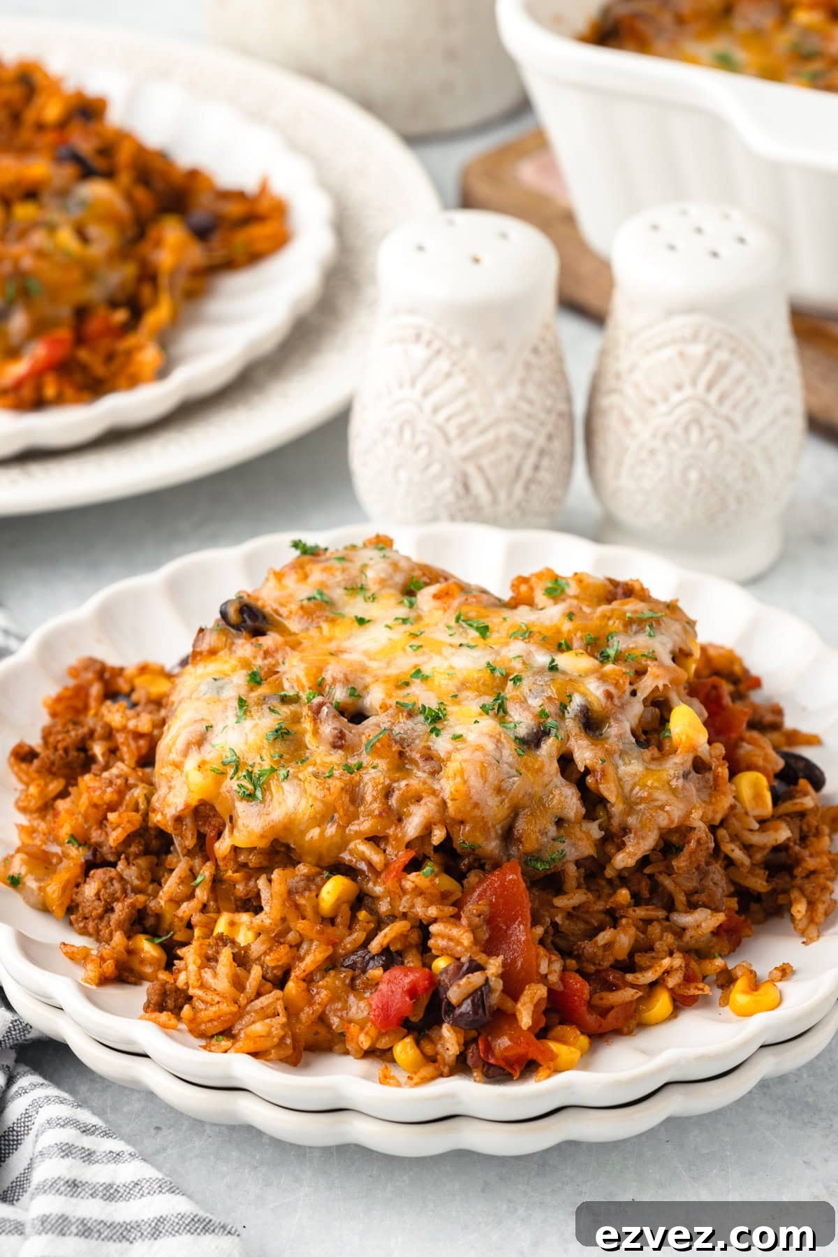 A serving of cheesy taco rice casserole on white plates.