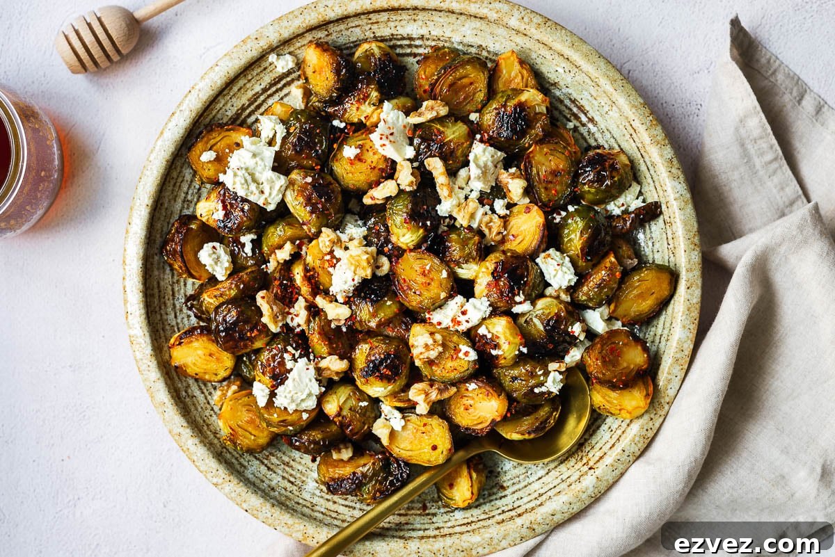 Roasted Brussels sprouts with honey glaze topped with feta and walnuts in a shallow serving bowl.