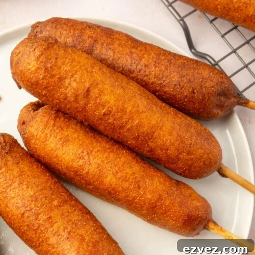 Golden-brown gluten-free corn dogs arranged on a white plate, ready to eat.