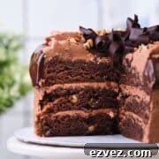 A three layer chocolate walnut cake cut open to show the moist layers.