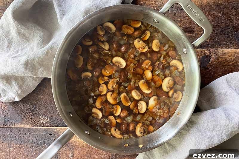 Leftover Pot Roast Mushroom Soup Recipe for Comforting Meals 11 Horizontal image of a broth with sliced vegetables in a pot.