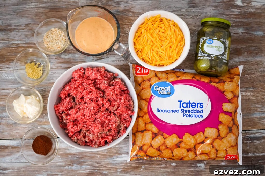 Big Mac Tater Tot Casserole Recipe: Cheesy Beef & Tots Bake 4 A 32 oz. bag of frozen tater tots, a jar of hamburger dill pickle slices, shredded cheddar cheese, thousand island dressing, 2 lbs. of raw ground beef, paprika, mayo, dried ground mustard, and dried minced onion on a wooden table.
