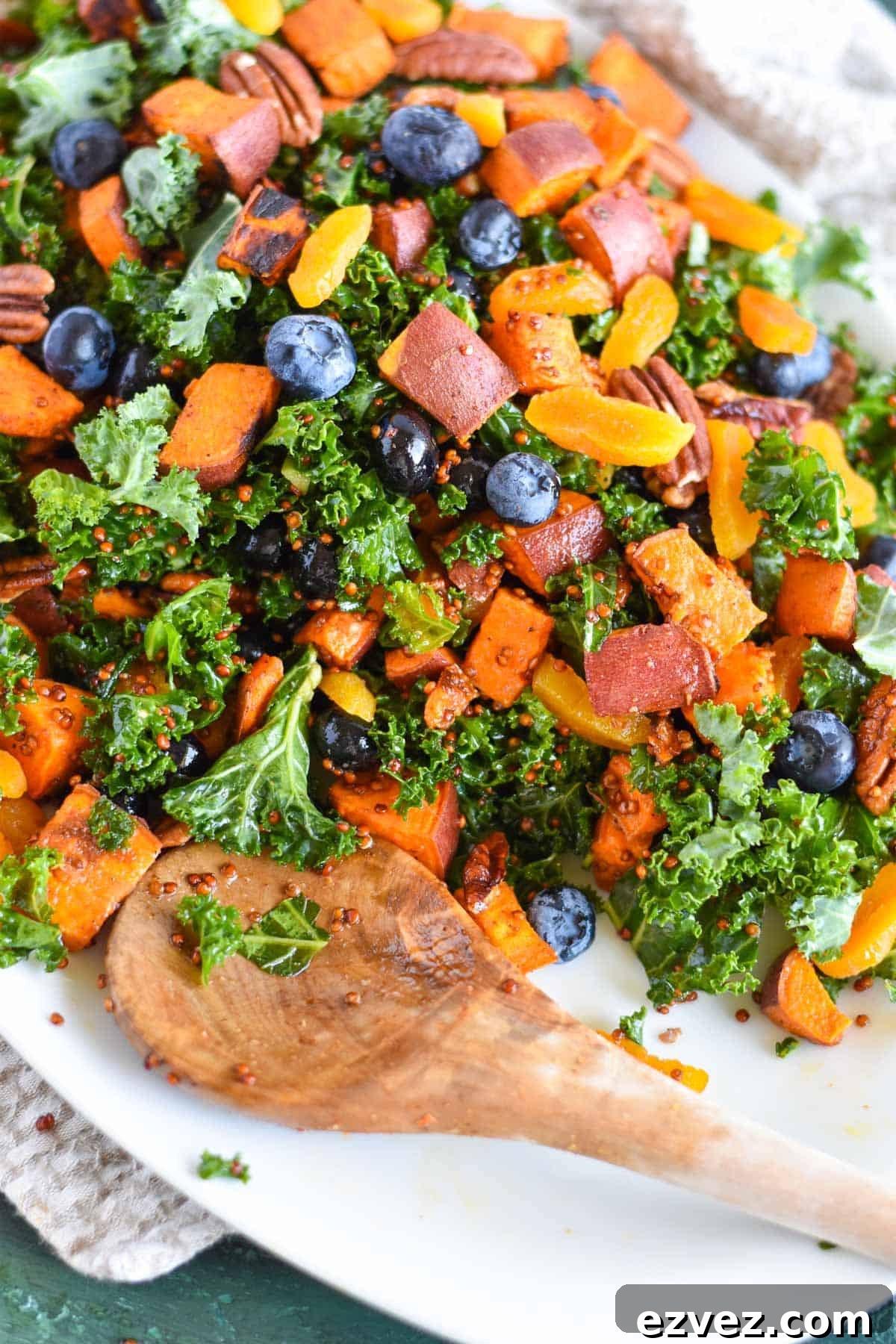 kale salad on white platter with wooden spoon on it. 
