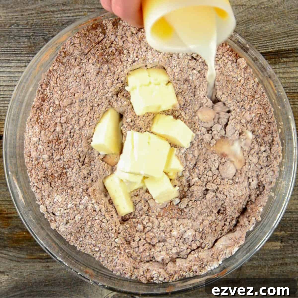 Adding butter and milk to powered sugar and cocoa powder.