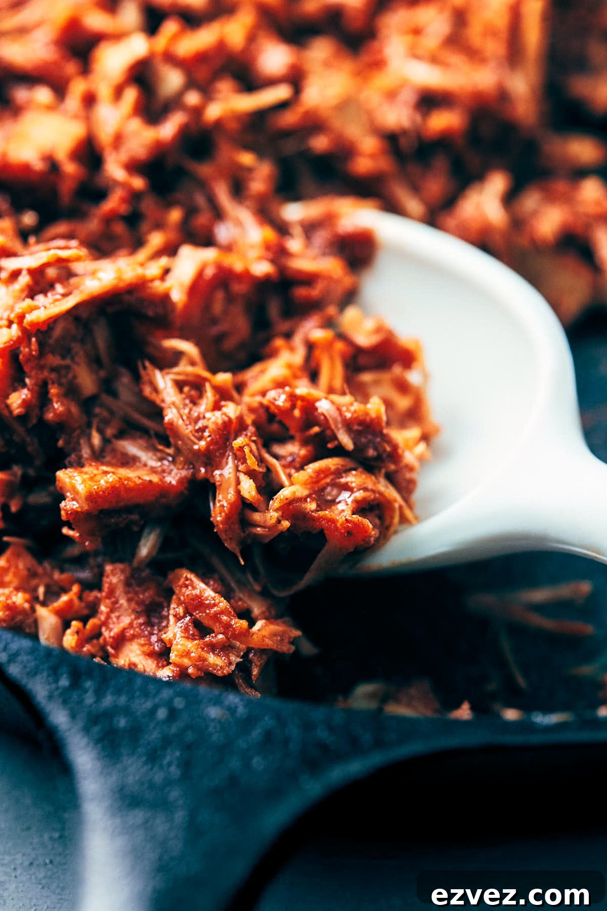 Vegan pulled pork being cooked down in a cast iron pan with barbecue sauce
