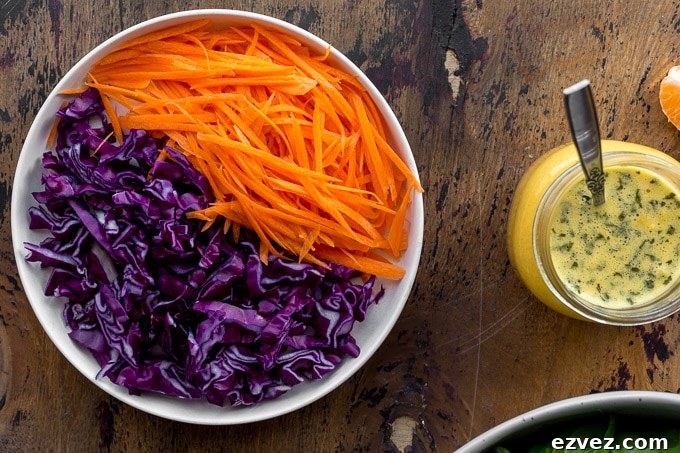 Shredded carrot and red cabbage on a plate next to a jar of dressing.