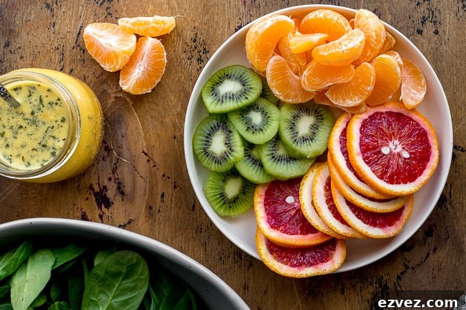 Sliced kiwis and oranges arranged on a plate.