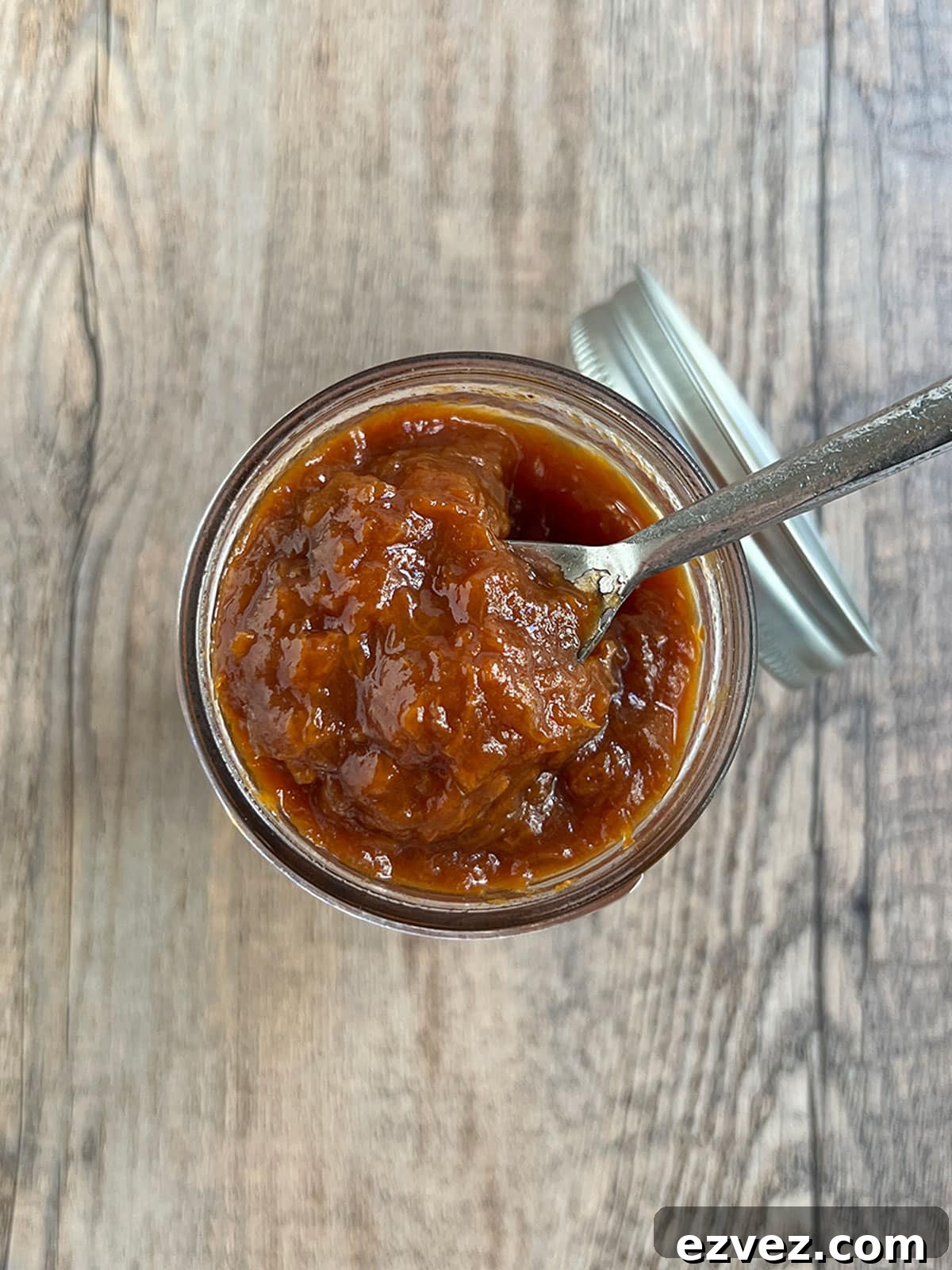 Apricot jam with brown sugar in a jar with a spoon on top.