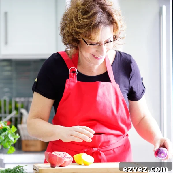 Beth Lee in red apron looking at vegetables on cutting board