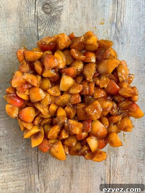 Apricots mixed up with sugar and macerating in a clear glass bowl.