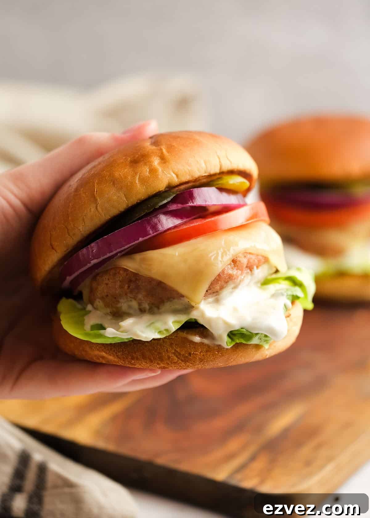 hand holding a loaded turkey burger with all the trimmings