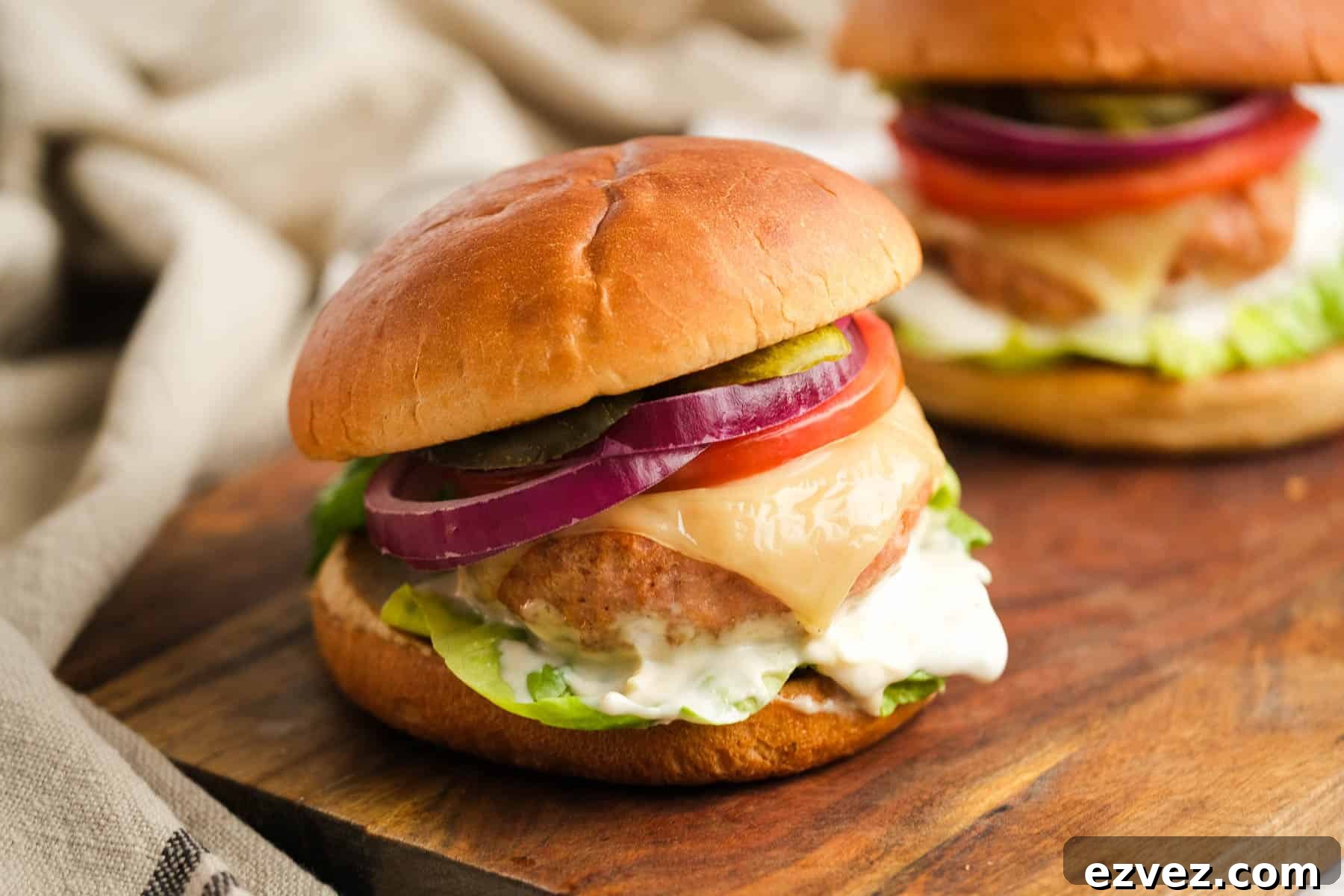 two turkey burgers with all the toppings on a cutting board