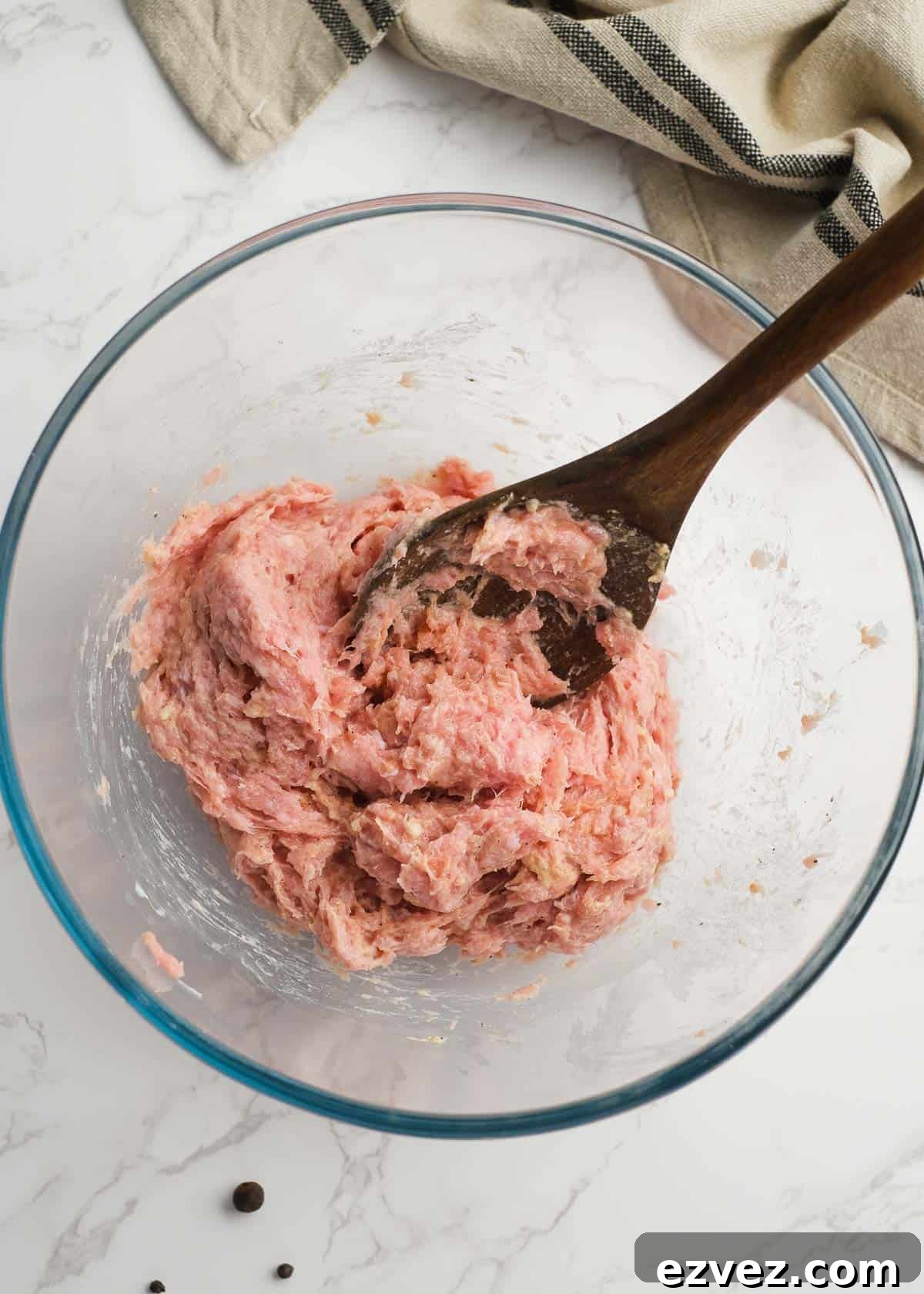 a spoon mixing the seasonings and mayonnaise into the ground turkey
