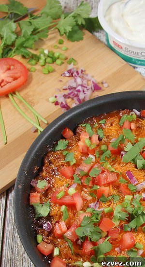 Finely chopped fresh veggies on a hot pan of black beans and seasoned ground beef.