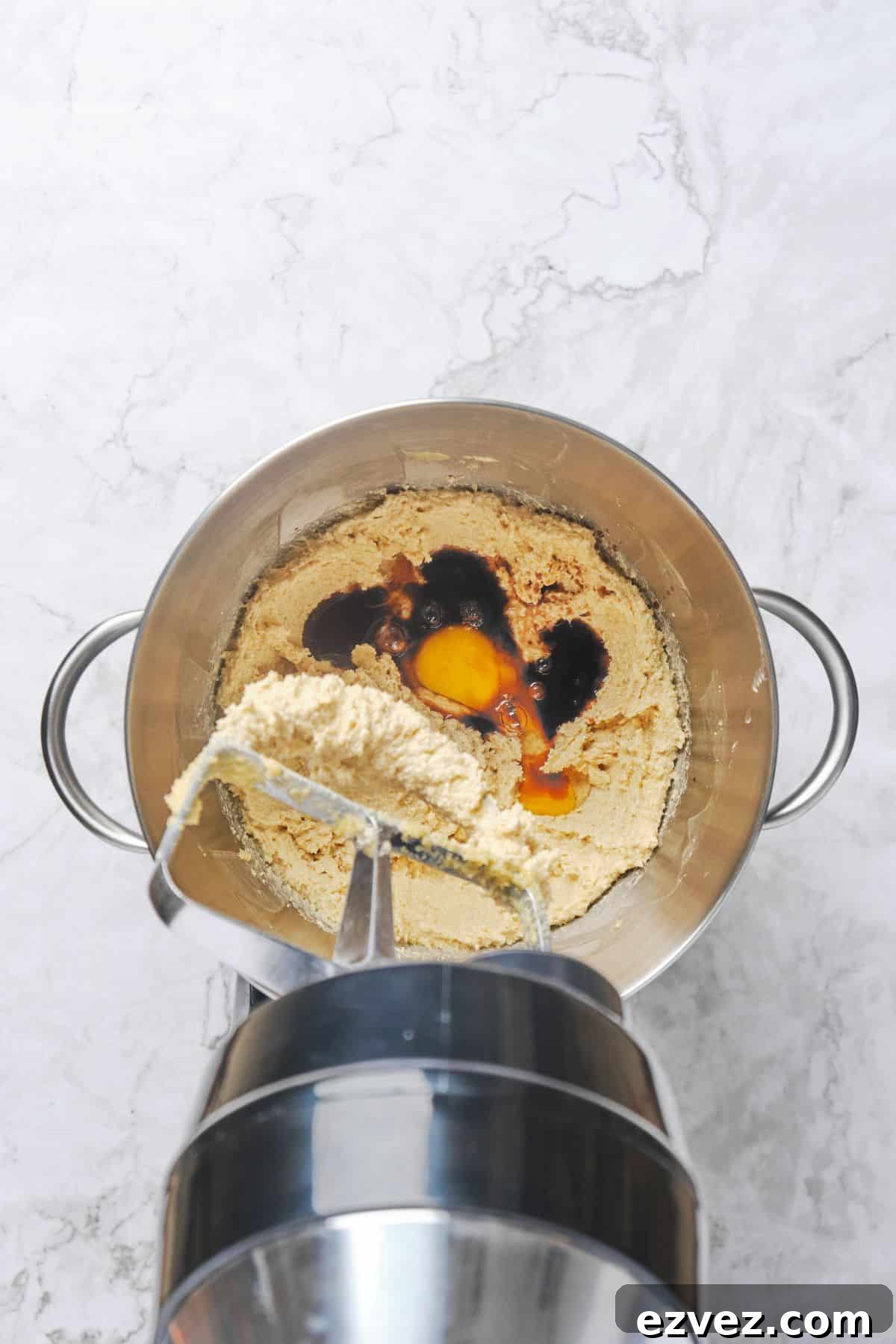 Egg and vanilla added to a stand mixer bowl of creamed butter, brown sugar, and white sugar.